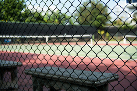 Bench beside the tennis court Looking through the iron fenceの写真素材