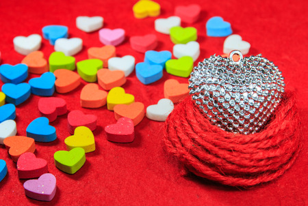 Valentines day background with silver heart and colorful heart shaped on red paper.