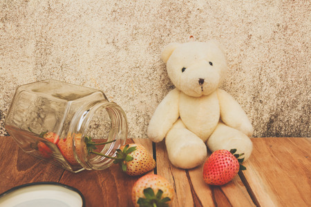 Strawberry jar and Teddy bear on a wooden, process color with Vintage Tones.の写真素材