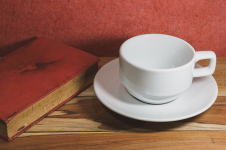 Empty coffee cup and old book on a wooden, Process color with Vintage Tones. Focusing on cup.の写真素材