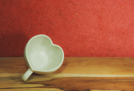 Heart shape coffee cup on wooden. Process color with Vintage Tones. Soft focus.の写真素材
