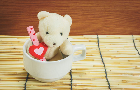 teddy bear with heart in coffee cup on a bamboo mat, process colorの写真素材