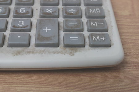 old and dirty calculator on wooden background, vintage tone process.の写真素材