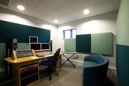 Sound studio with keyboard, a sound board, speakers and monitors plus green sound absorbers on the walls,の写真素材