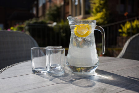 Refreshing jug of water with slices of fruit and two glasses