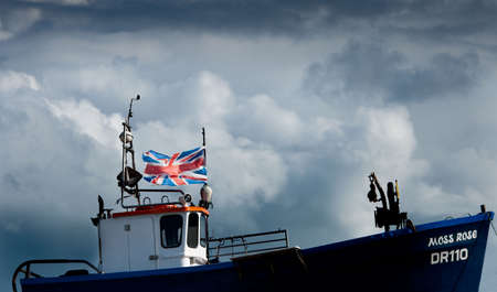 Dark clouds gather over UK fishing trawler with the British Union Jack flyingのeditorial素材