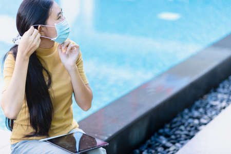Asian woman wearing a mask sitting at the pool to protect against air pollution