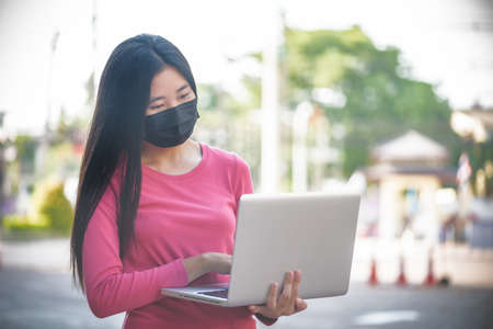 Asian woman wearing a protective face mask working with laptopの写真素材