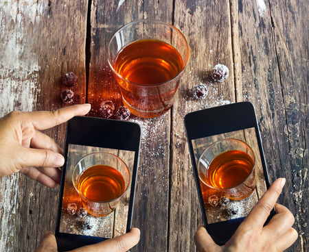 Smartphone take photos of tea and grape on wooden background, vibrant conceptの写真素材
