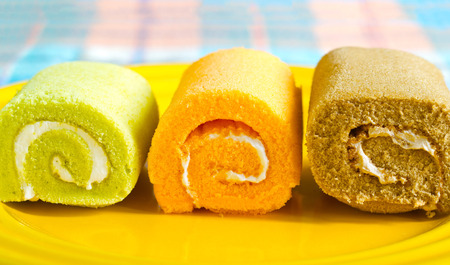 Colorful vibrant roll cake on yellow plate, soft and blur conceptの写真素材