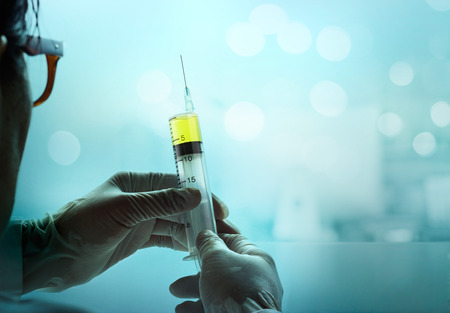 syringe in hand glove on blue lab medical background