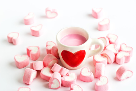 red heart symbol on strawberry milk cup and pink candy heart on white backgroundの写真素材