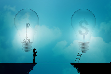 business woman stand on a cliff  with key and dollar signs in light bulbs on a blue background, business conceptの写真素材