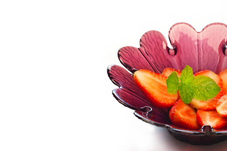 strawberry slice and mint in purple flower shape bowl on white background, soft focusの写真素材