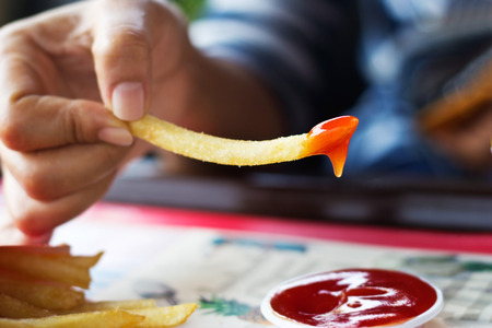 French fries with ketchup in hand on table, soft focusの写真素材