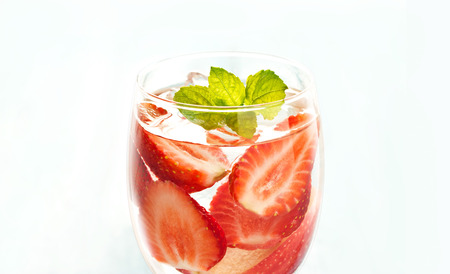 glass delicious refreshing drink of strawberry and apple with mint on blue background, infusioned water, soft focus and warm color toneの写真素材