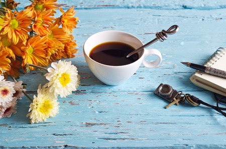 coffee cup and vibrant flower, paper note of vintage pastel color tone style on blue wooden, soft focusの写真素材
