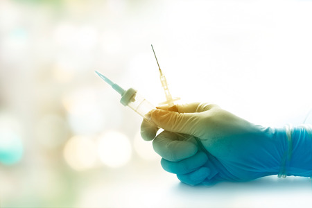 colorful sterile syring and glove doctor getting ready to inject patient on soft background, vibrant conceptの写真素材
