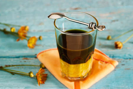 vintage color tone style of ingredient green tea latte layers and spoon on fabric and blue wooden background soft focus and blurの写真素材