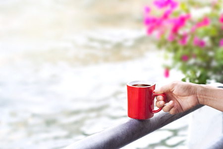 coffee red cup on a fence of canal nature backgroundの写真素材