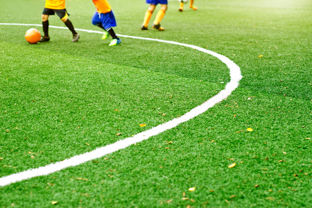 Green soccer field grass with white mark line and the boys play football background, soft focusの写真素材