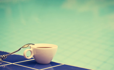 Vintage color tone style cup of coffee on the swimming pool, soft focus and blank text