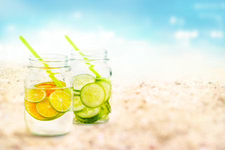 Infused water lemon and cucumber in mug on sea sand beach summer day and nature background