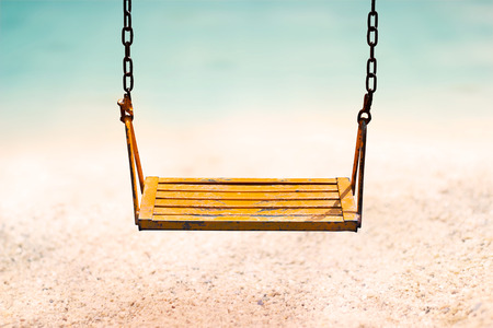 vintage color tone style of yellow swing on sand sea beach summer dayの写真素材