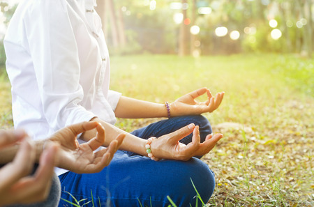 women meditating outdoors in green park, worm color toneの写真素材