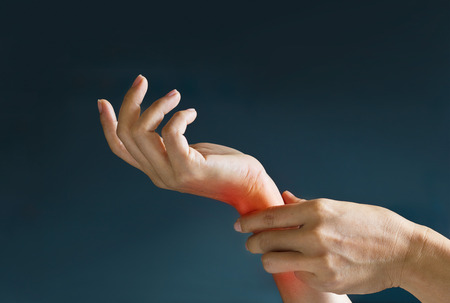 Acute pain in a woman wrist, colored in red on dark blue background. Health issues problemsの写真素材