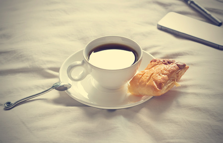 coffee cup and pie in the morning on the bed background, vintage color toneの写真素材