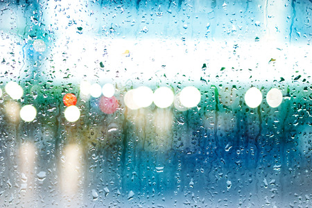Abstract drops of rain on colorful glass background, street Lights, soft focus