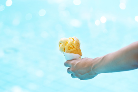 woman holding melting ice cream in waffles cone in hands on pool backgroundの写真素材