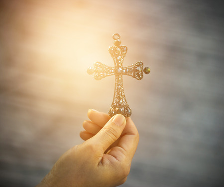 The Cross crystal with sun light vibrant in hand , warm color tone