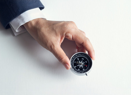 Businessman with a compass holding in hand on paper backgroundの写真素材