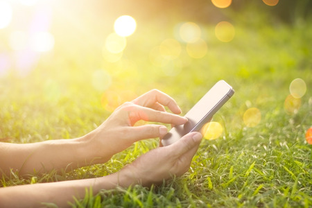 woman using mobile smart phone outdoor in the sunrise on nature backgroundの写真素材