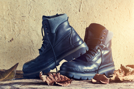 A pair of black leather men's boot with dry leaf on wooden and paper texture backgroundの写真素材