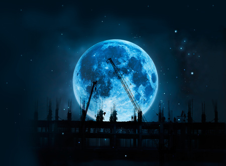 Construction site with cranes and workers full blue moon at night background, Moon original image from NASA.govの写真素材