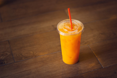 Orange juice glass on wooden floor background, Warm color toneの写真素材