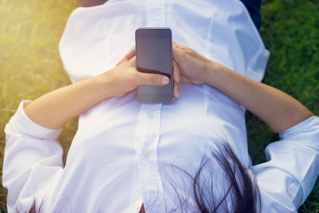 Woman with mobile smart phone in hand relax on the parkの写真素材