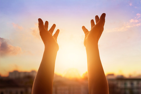 Respect and pray on the sunset in city background