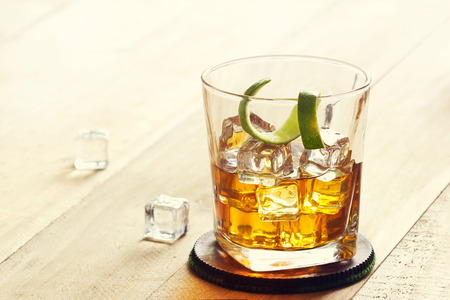 Glass of whiskey with ice on wooden background, warm color toneの写真素材