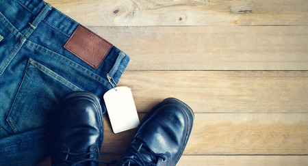 Blue jeans with white blank tag and shoes on wooden background, blank textの写真素材