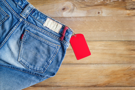 Blue jeans with red blank tag on wooden backgroundの写真素材
