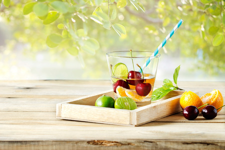 healthy detox water, glass of cherry, orange and lime on wooden tray and pastel color nature backgroundの写真素材