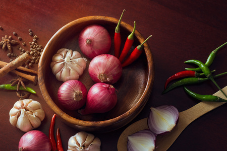 Fresh herbs and spices, onion slices and garlic, and hot peppers scattered on wooden surface, spicy conceptの写真素材