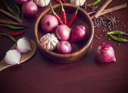 Fresh herbs and spices, onion slices and garlic, and hot peppers scattered on wooden surface, pices conceptの写真素材