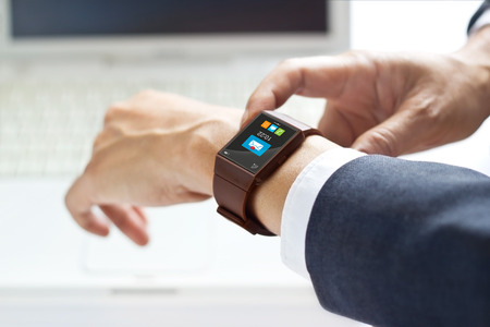 On office a man using his smartwatch on laptop backgroundの写真素材
