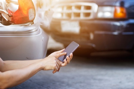 Man using smartphone at roadside after traffic accidentの写真素材