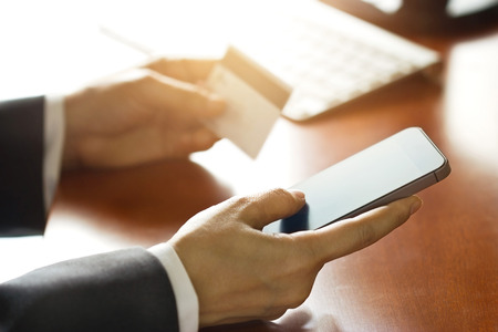 Mobile payments, business man using smartphone and credit card for online shopping, soft focusの写真素材